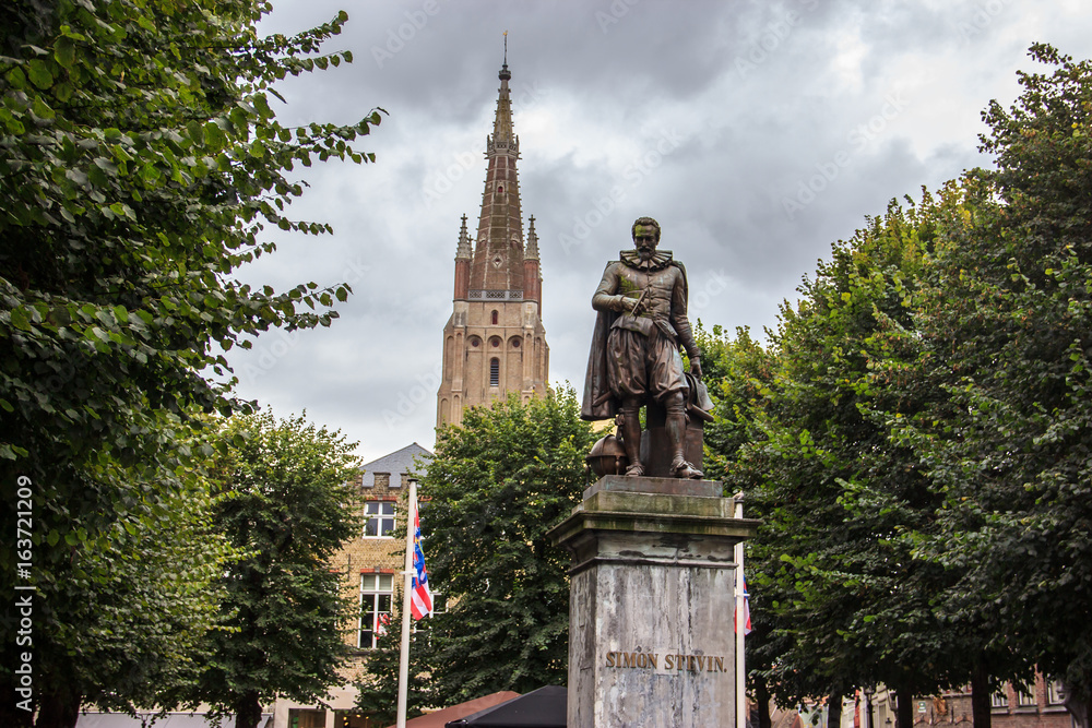 Simon Stevin Bronze Statue in Bruges with park and church as background, Bruges, Belgium, Europe.