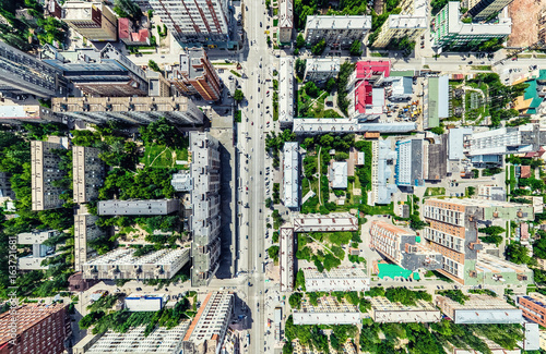 Aerial city view with crossroads and roads, houses, buildings, parks and parking lots, bridges. Helicopter drone shot. Wide Panoramic image.