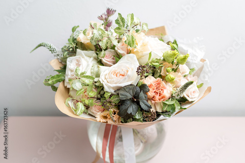cute light bouquet with garden roses and mixed flowers on pink table