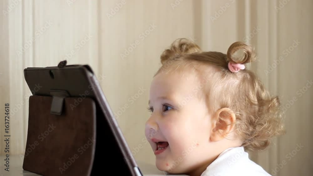 Device baby with the tablet with a large screen plays and laughs. Device baby with the tablet with a large screen plays and laughs.