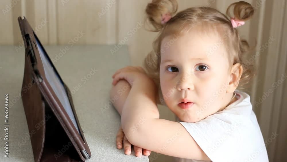 A cute little baby girl watching a movie on an tablet A cute little baby girl watching a movie on an tablet