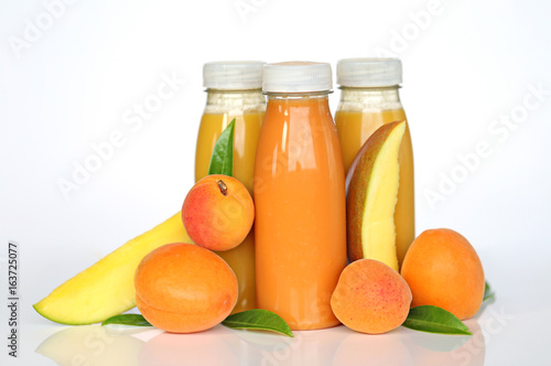 Orange smoothies of mango and apricots in plastic bottles on a light background
