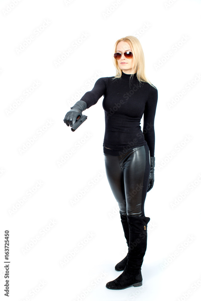 Fototapeta premium Young blonde woman in a black suit with a gun