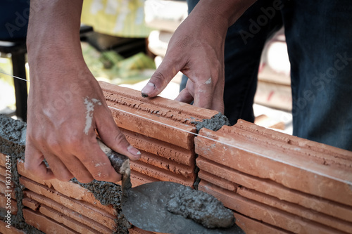 Bricklayer worker installing brick masonry on exterior wall. © nipaporn