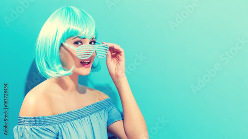 Beautiful woman in a bright blue wig on a blue background