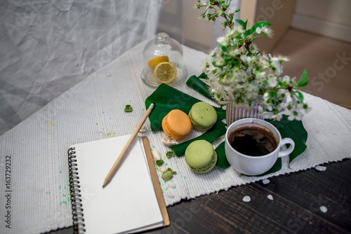 Morning tea or coffee with orange and kiwies slices and green macaroons on a white blanket with cherry blossom photo