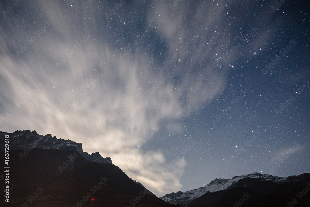Mountain with little snow on the top and moving cloud in the blue color night with stars in winter at Lachung in North Sikkim, India. Mountain with little snow on the top and moving cloud in the blue color night with stars in winter at Lachung in North Sikkim, India.