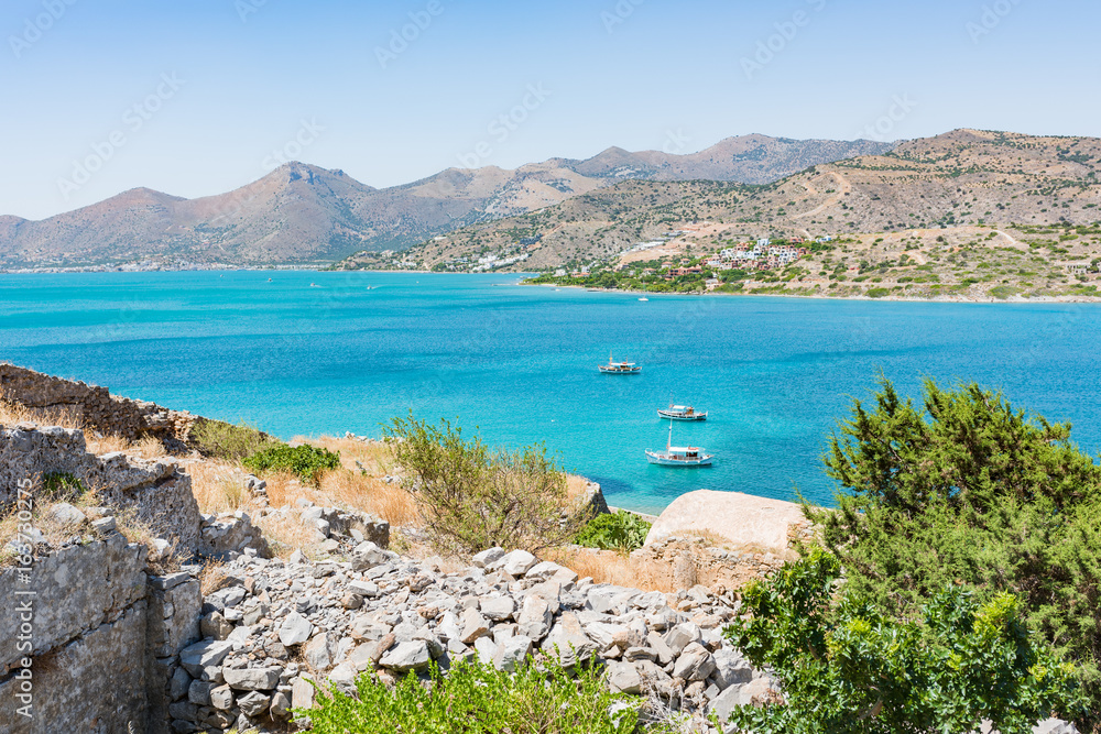 Ruins on top of Spinalonga. Picturesque view to the blue sea and island with mountain.