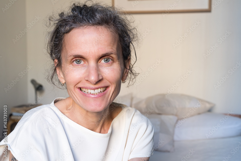 Portrait of happy smiling natural looking middle aged woman in bedroom (selective focus) Portrait of happy smiling natural looking middle aged woman in bedroom (selective focus)