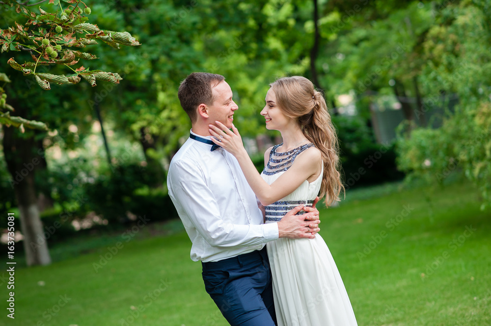 A married couple is walking and hugging in the park.