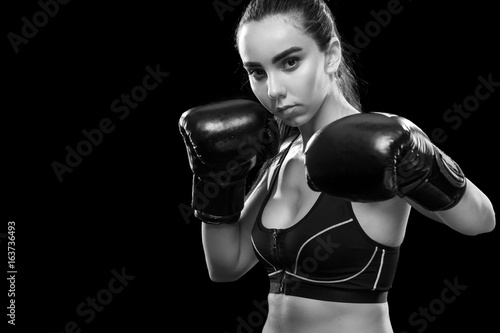 Woman boxer fighting in boxing cage. Isolated on black background. Copy Space. Black and white photo. Sport concept.