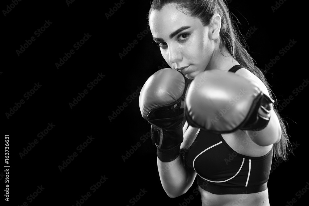 Woman boxer fighting in boxing cage. Isolated on black background. Copy Space. Black and white photo. Sport concept.