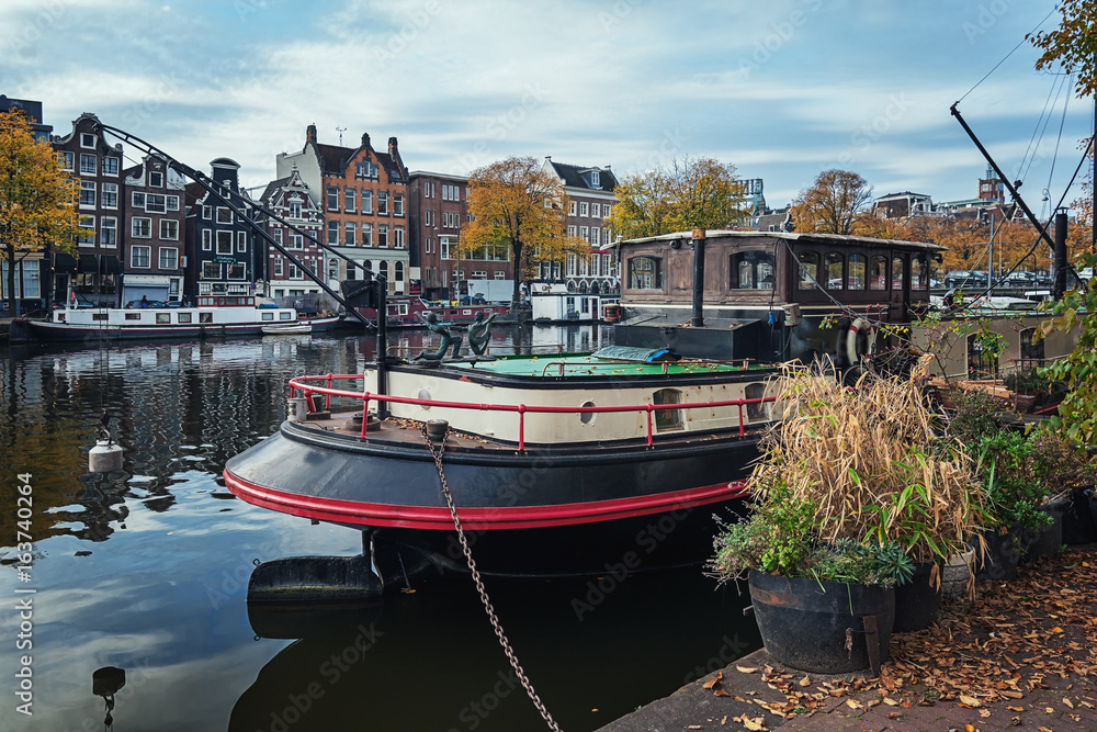 Boat docked at the quay along the Amstel river in the old town of Amsterdam