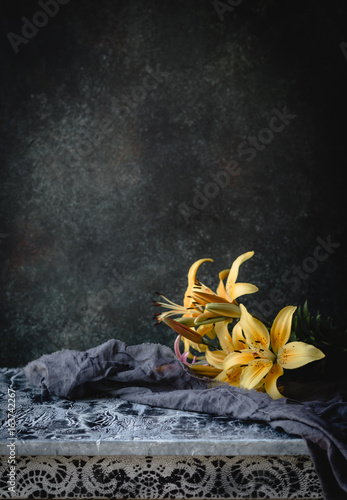 yellow lilies on an old colored table with textile on a green background with vignette, toned for a vintage effect, copy space