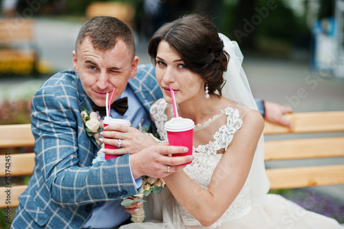 Newly married drinking beverages in the street on their wedding day.