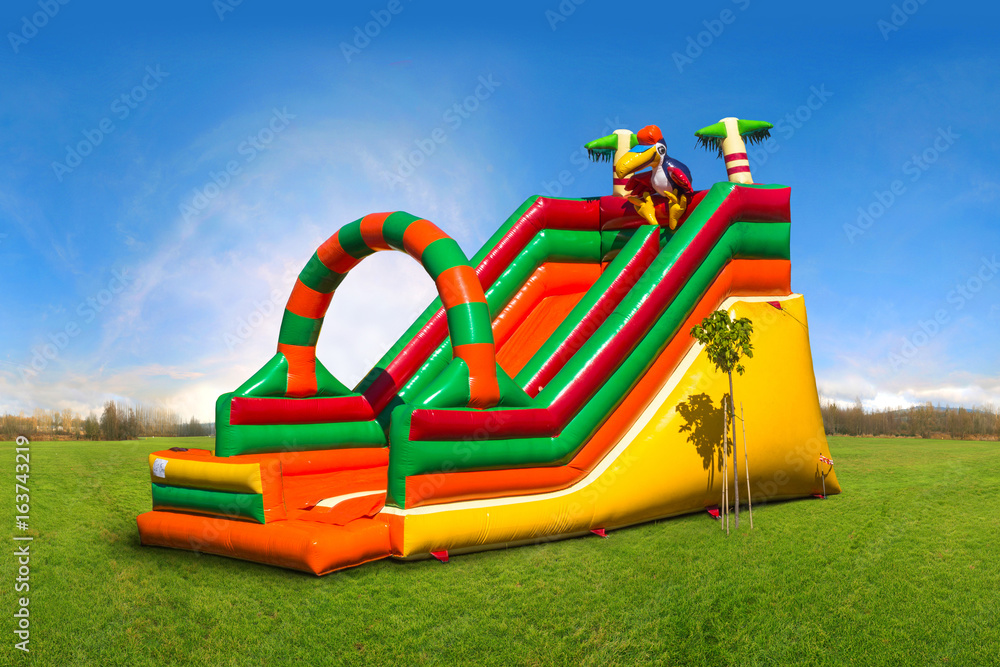Colorful, large, inflatable children's slide on the green grass