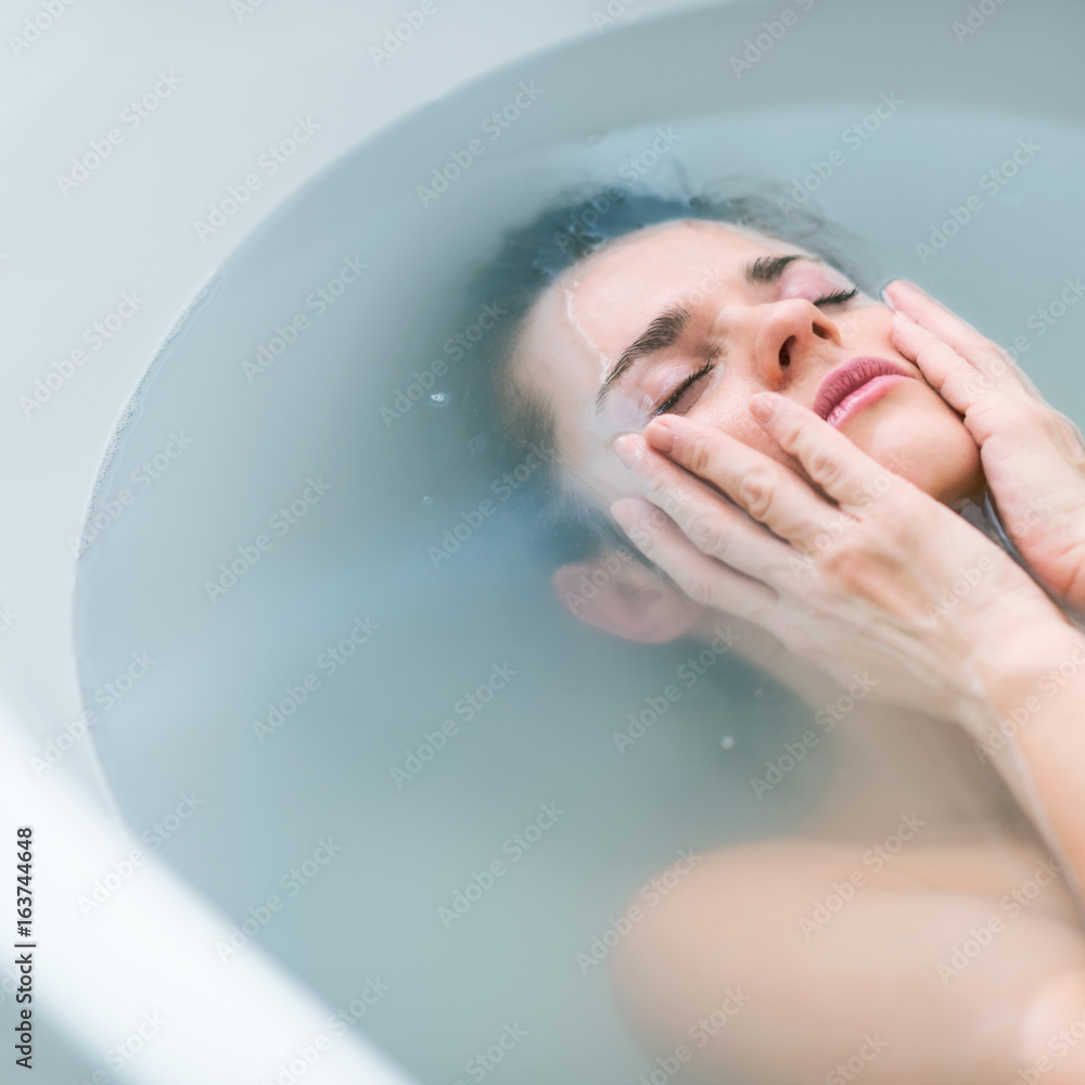 Fototapeta premium Frustrated young woman laying in bathtub