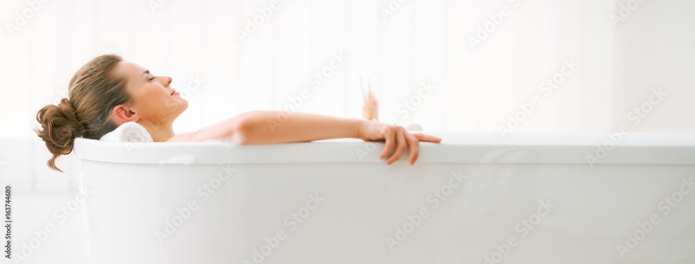 Relaxed young woman laying in bathtub - obrazy, fototapety, plakaty 