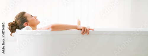 Slika na platnu Relaxed young woman laying in bathtub