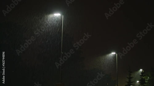 Rainy street at night. A row of lampposts illuminating raindrops. Long shot. photo