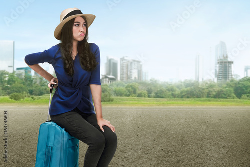 Traveler asian woman with hat sitting on a suitcase
