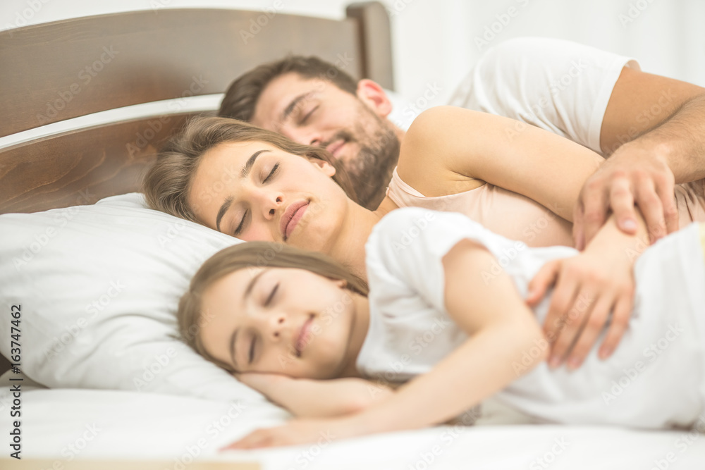 The daughter and parents sleeping in the bed