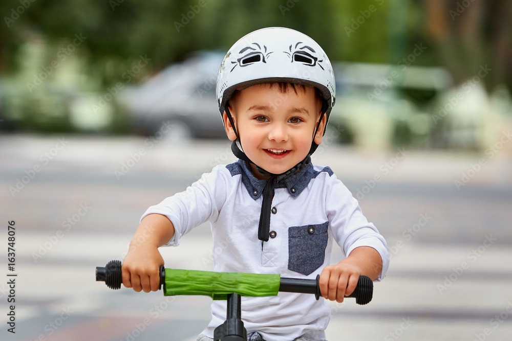 Child boy in white helmet riding on his first bike with a helmet. Bike without pedals. Child boy in white helmet riding on his first bike with a helmet. Bike without pedals.