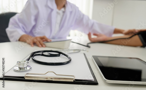 Stethoscope with clipboard and Laptop on desk, Doctor working in hospital writing a prescription, Healthcare and medical concept, test results in background