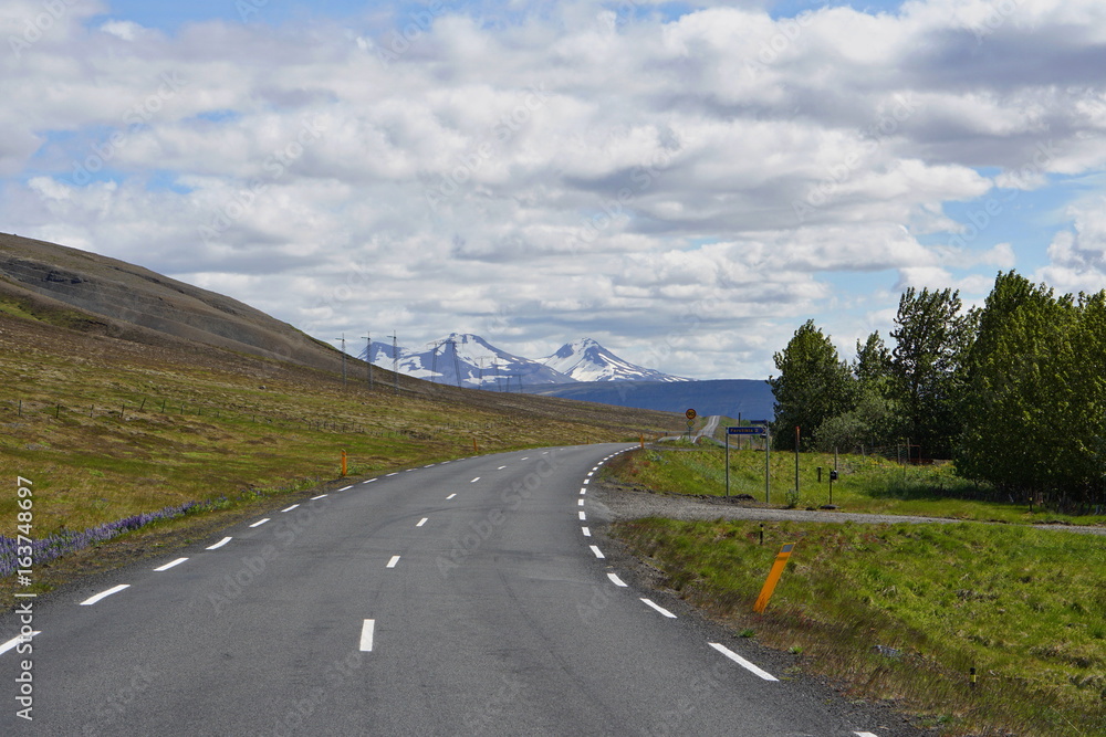 Scenic Icelandic road for cars with green mountains in the background 