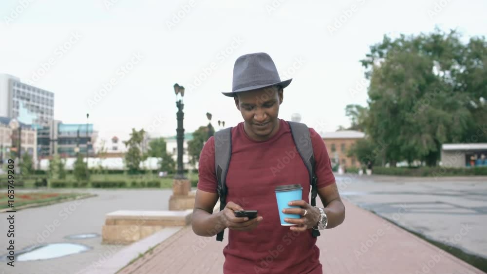 Steadicam shot of smiling tourist man walking and surfing smartphone near famous historical place in Europe Steadicam shot of smiling tourist man walking and surfing smartphone near famous historical place in Europe