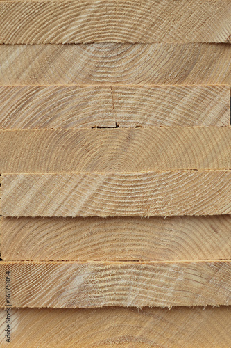 Close-up pattern of stacked rectangular wooden beam timber at sawmill lumberyard.