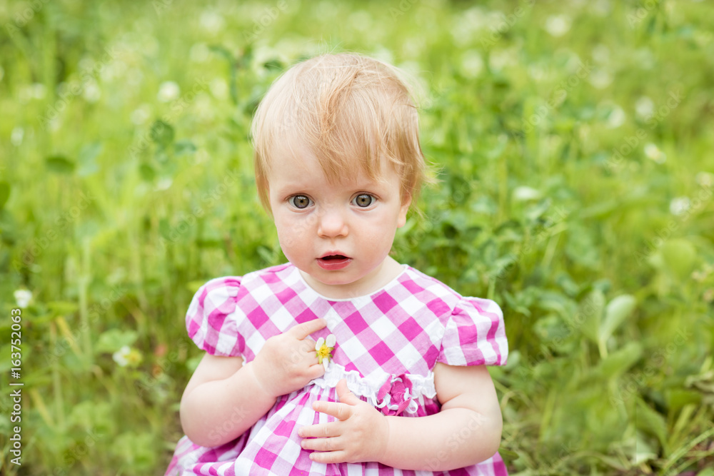 Portrait of a beautiful baby girl sitting on green meadow Portrait of a beautiful baby girl sitting on green meadow