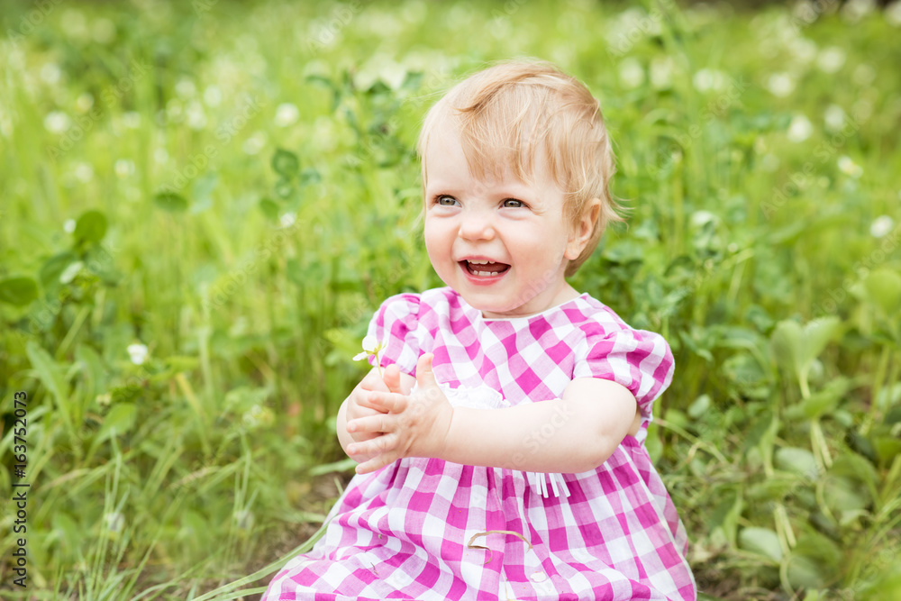 Portrait of a beautiful baby girl sitting on green meadow Portrait of a beautiful baby girl sitting on green meadow