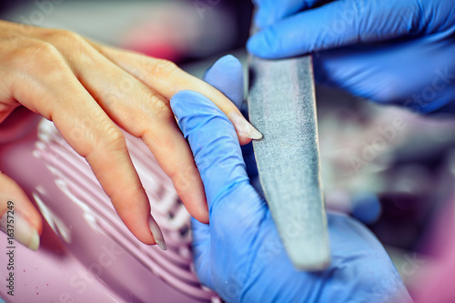 Girl in gloves handles nails with a milling cutter for manicure