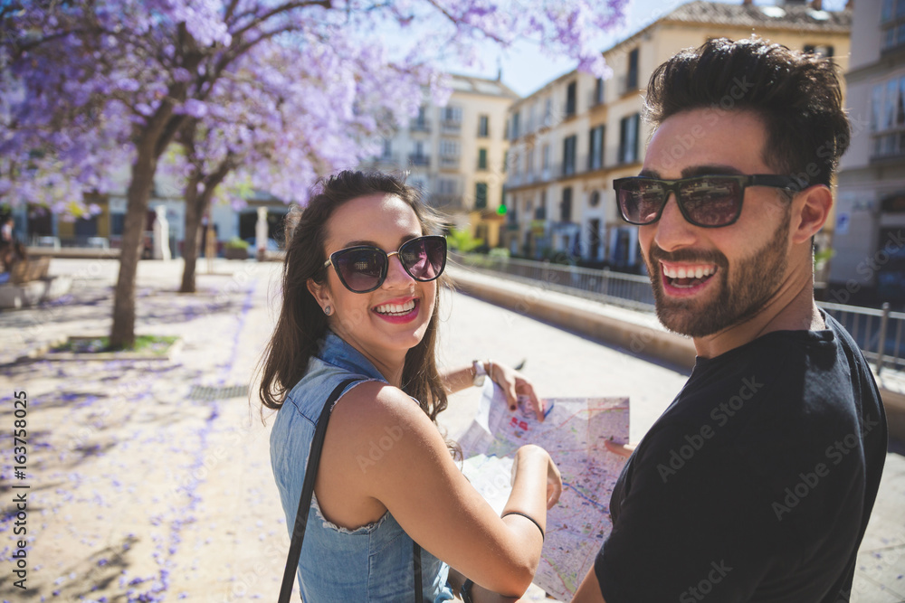 Happy tourist couple at town holding map laughing Happy tourist couple at town holding map laughing