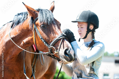 Young teenage girl owner harnessing bay stallion for training © AnnaElizabeth