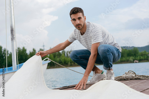 Young man folding boat's sail
