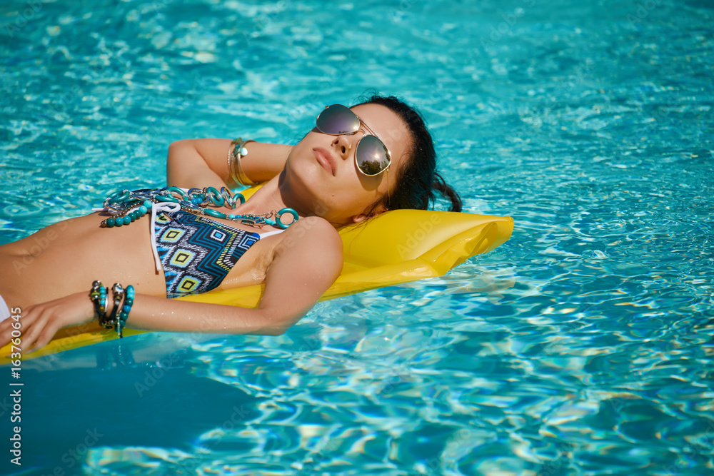 Young happy woman relaxing in a swimming pool