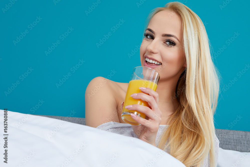 Attractive woman drinking orange juice sitting on her bed Attractive woman drinking orange juice sitting on her bed