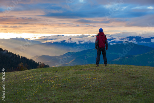Lonely traveler admires the epic sunset in the mountains © sanechka
