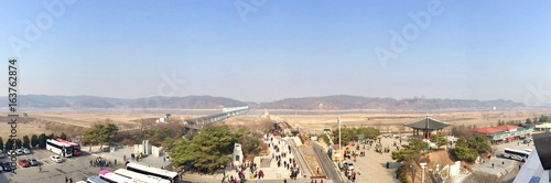 Panoramic view of tourists visiting the no-man's-land between the border of North & South Korea (Asia) in Imjingak: brown sand desert, hills / mountains separate the demilitarized war zone (DMZ)