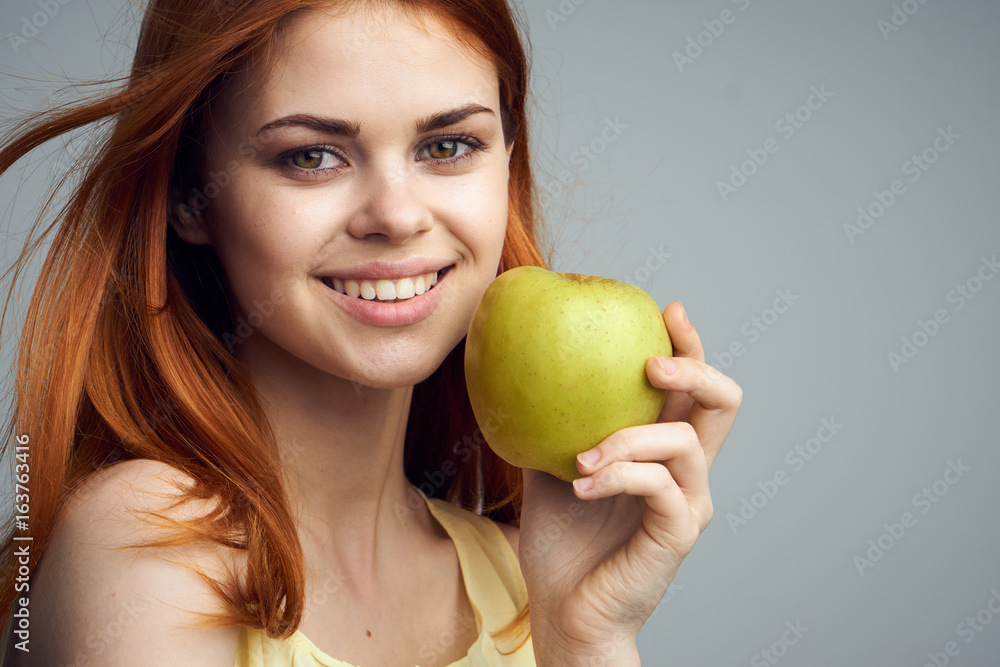 Beautiful young woman on a gray background holding an apple Beautiful young woman on a gray background holding an apple