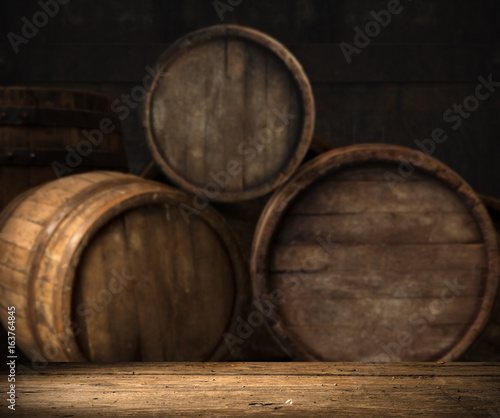Old oak barrel on a wooden table. Behind blurred dark background. © kishivan