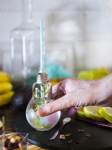 Man preparing and drinking cold infused water with lemon, with straw. Fresh, summer mood. photo