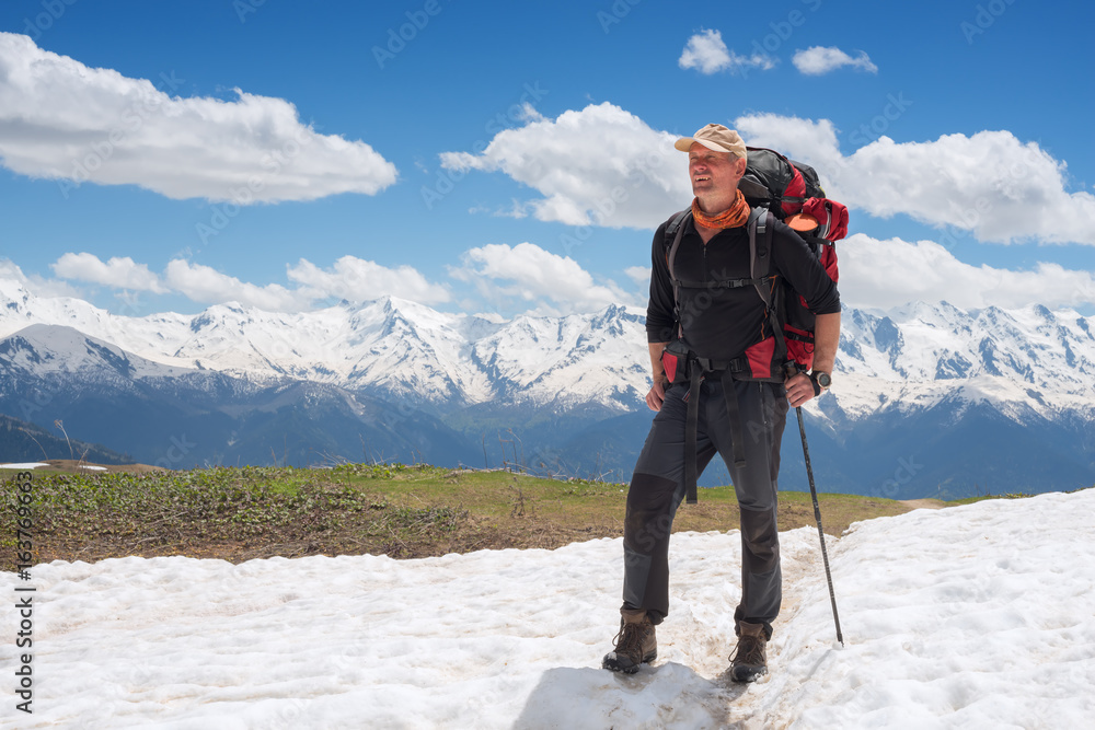 Confident man traveler with big backpack on the mountain trail