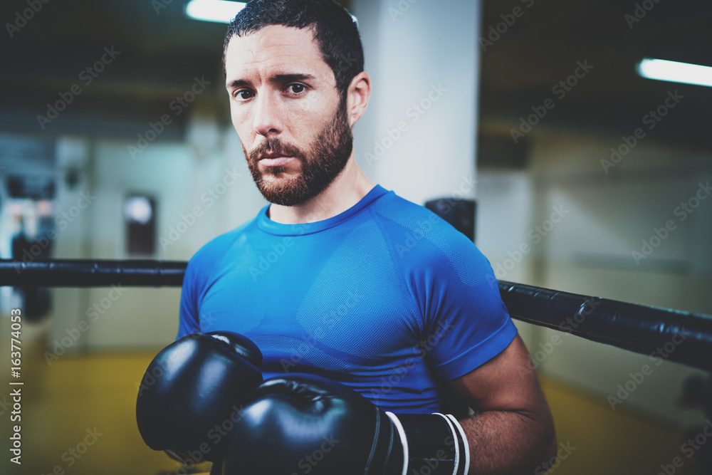 Young caucasian athlete in black gloves looking at the camera.Blurred background.Horizontal. Young caucasian athlete in black gloves looking at the camera.Blurred background.Horizontal.
