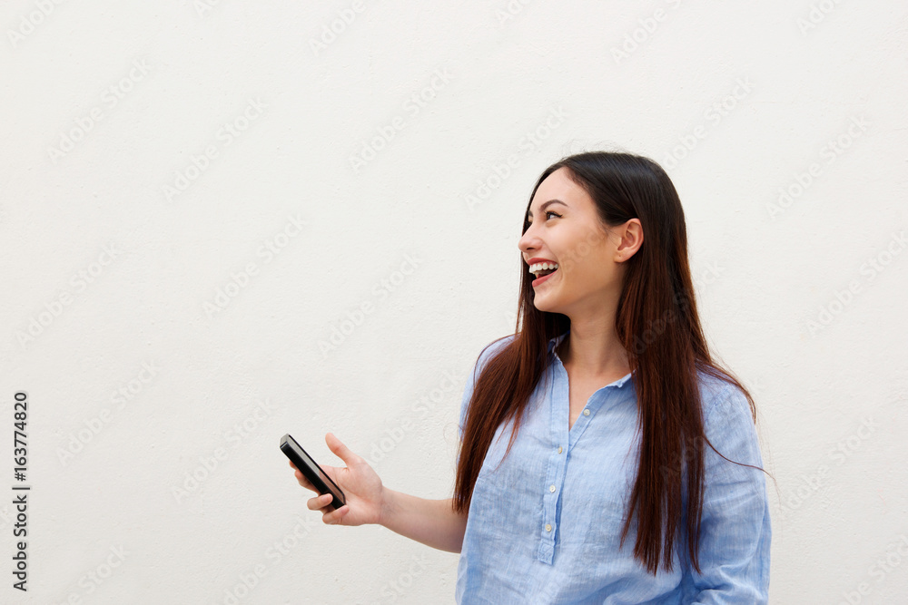 Side portrait of laughing woman with long hair holding mobile phone Side portrait of laughing woman with long hair holding mobile phone