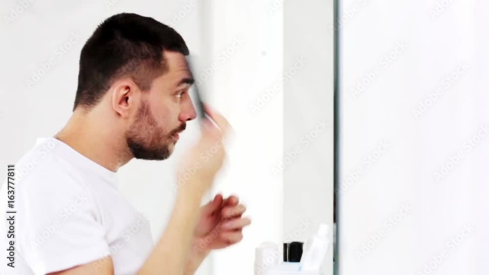 happy man brushing hair with comb at bathroom happy man brushing hair with comb at bathroom