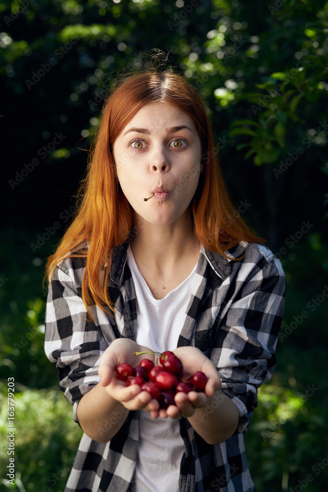 Beautiful young woman in the garden holds a cherry Beautiful young woman in the garden holds a cherry