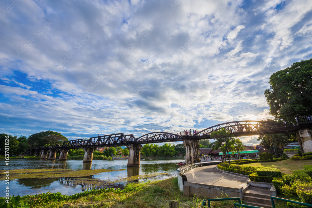 Fototapeta premium Bridge River Kwai with sky and sun in Kanchanaburi, Thailand